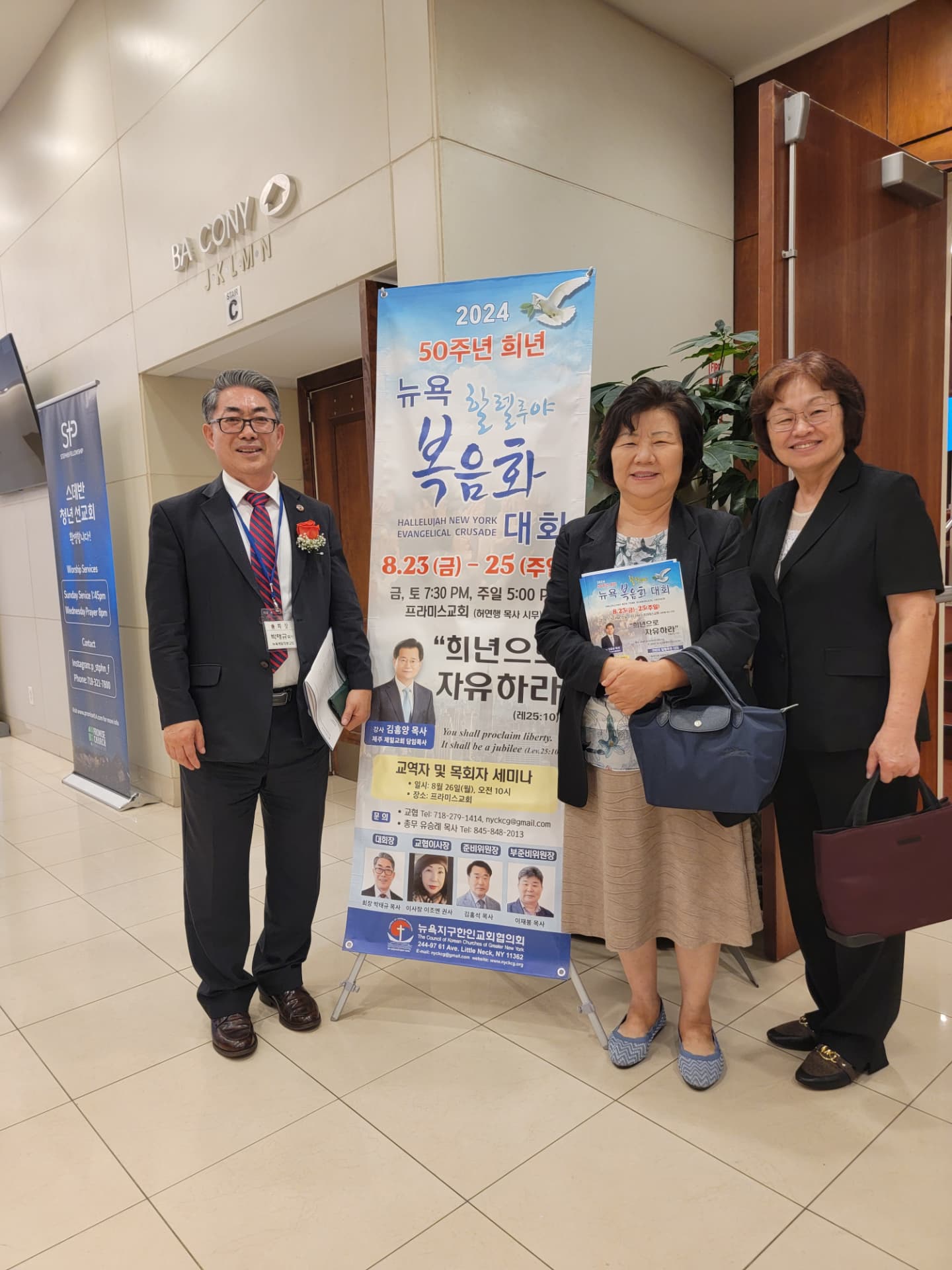 「50주년 희년 뉴욕 복음화 대회」 현수막 앞에 선 박태규 목사와 사모님